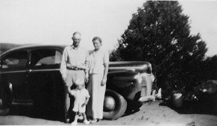 <Adron Terry and Johnie posed by their black 1940 ford. Location the breakse>