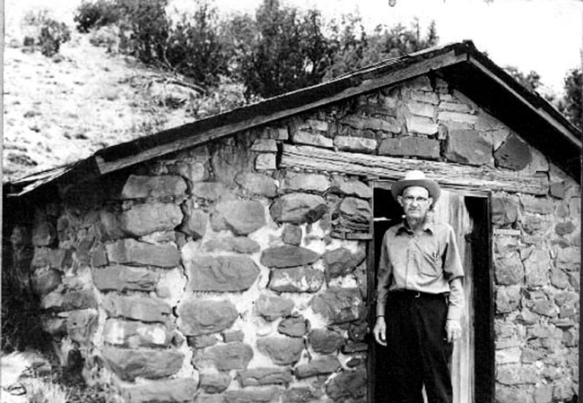 <adron turner posed in front of a rock building at the CCC camp on his ramon ranch>