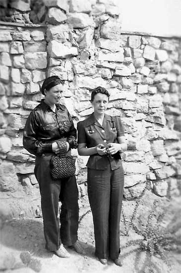 <johnie and pauline brooks standing in front of a rock building. Dressed alike>