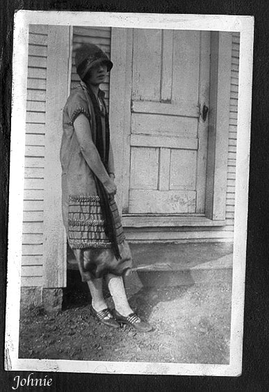 <johnie, with hat and white stockings, leaning against a house>