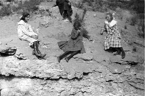 <four girls sitting on bluff in sunday clothes>