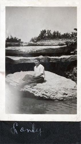 <sandy sitting by river bank on a rock>