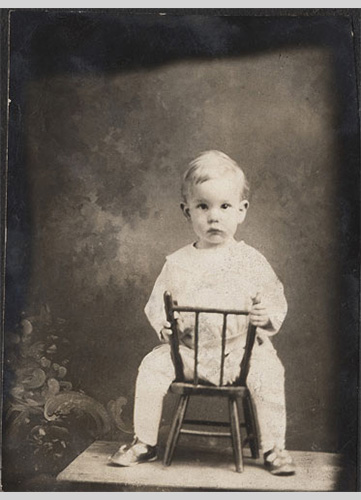 <little boy riding a chair studio portrait>