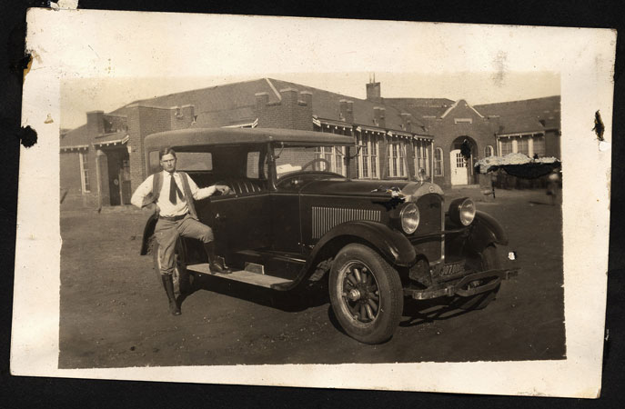 <man with big car standing in front of school building restored by terry>