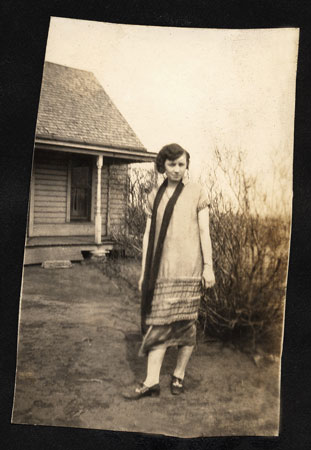 <mom johnie poses by leafless bush. favorite photo. dressed for church.>