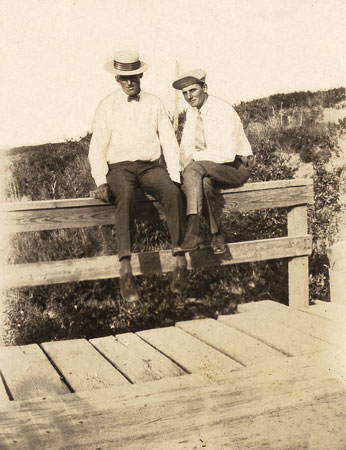 <two men sitting on bridge railing>