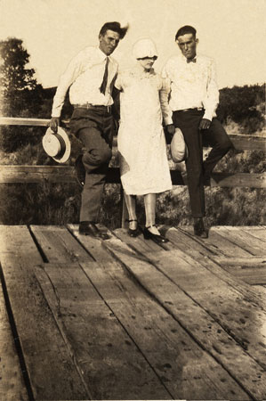 <two men and a lady sitting on birdge railing. windy day>