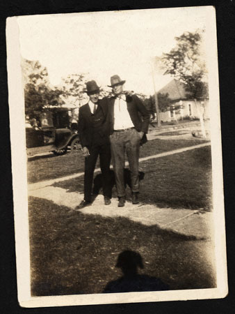 <Two Men standing on a sidewalk - Big Hats
Model A in Background >