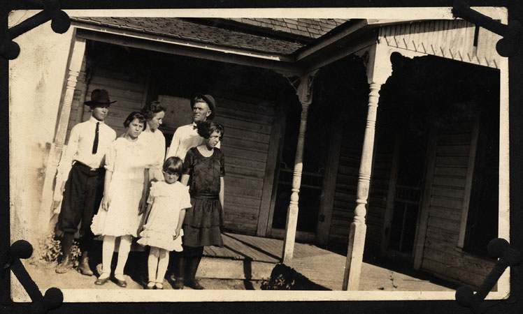 <Burt, Mary, Bruce, Pauline, Pearl and LaNell Downer stand in front of their house restored by terry>