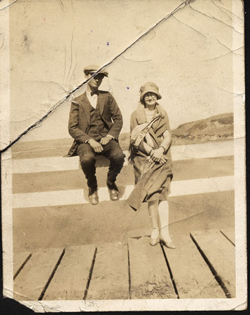 <man wearing a golf cap and a lady standing on a wooden bridge>