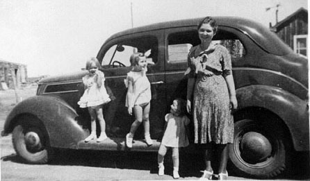 <adrienne donna sheila mildred turner girls standing on running board of old car rock house and ranch house can be seen in the background>