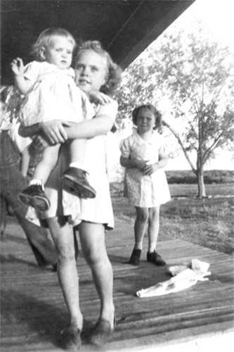 <janell holding a baby on front porch of farm house bula enoch>
